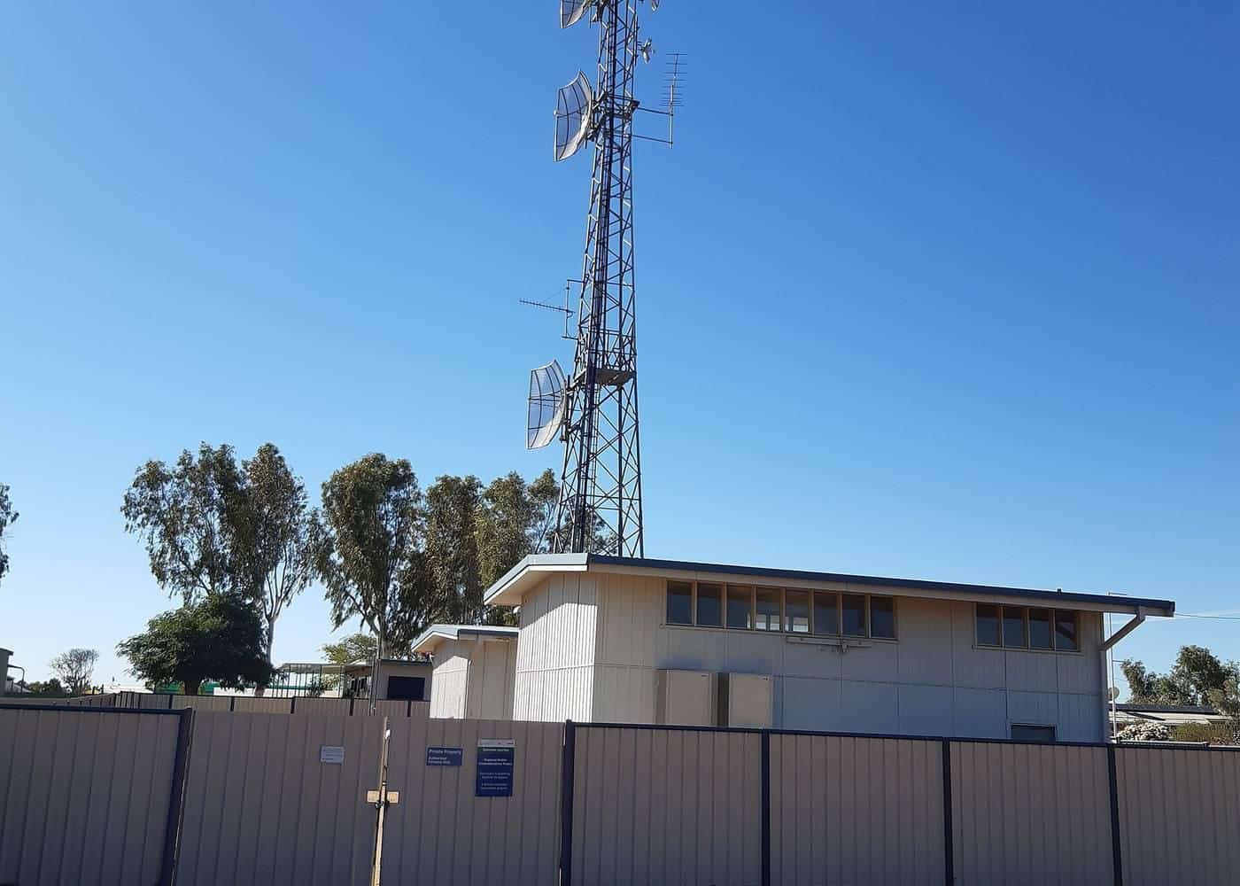 Mobile phone tower beside a building in an outback town under blue sky